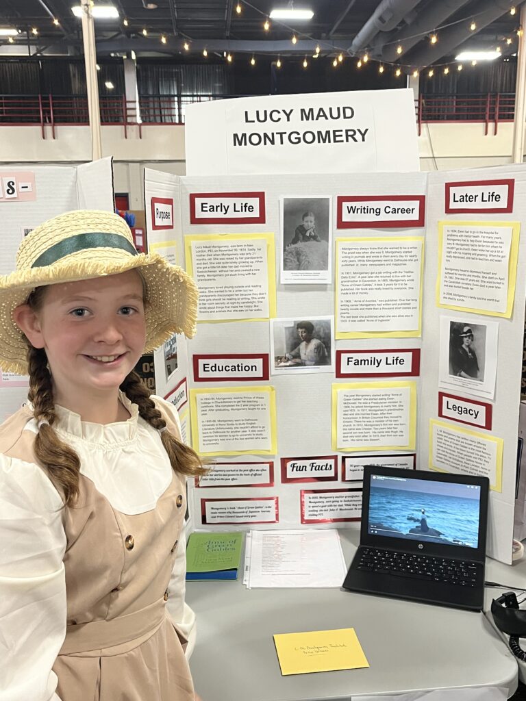 young girl with braids in her hair standing in front of a poster board with LMM info