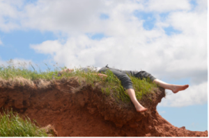 a woman's legs hanging over the edge of a red-soiled cliff